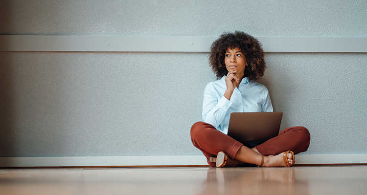Woman sitting cross-legged on the floor, deep in thought.
